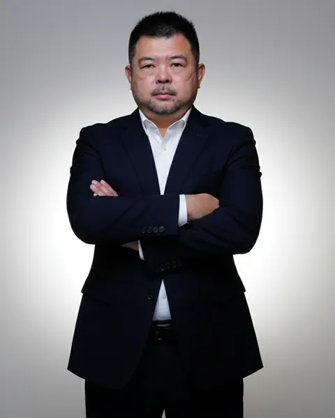 Coach BK Han, AI Innovation Coach in Singapore, standing in a navy suit with arms crossed